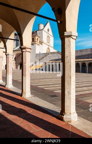 Blick durch Säulen auf die Basilika des hl. Franziskus von Assisi in der Morgensonne, Umbrien, Italien Stockfoto