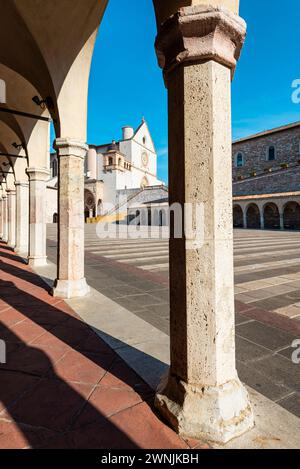 Blick durch Säulen auf die Basilika des hl. Franziskus von Assisi in der Morgensonne, Umbrien, Italien Stockfoto