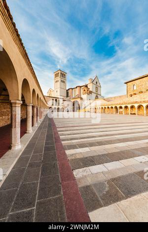 Kolonnaden umgeben den unteren Platz vor der Basilika des hl. Franziskus von Assisi im Abendlicht in Umbrien, Italien Stockfoto