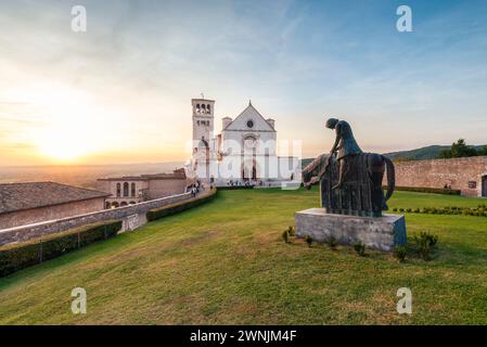 Die Basilika des hl. Franz von Assisi mit einer bronzenen Reiterstatue bei Sonnenuntergang, Umbrien, Italien Stockfoto