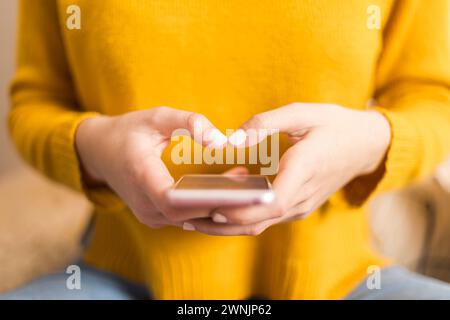 Nahaufnahme der Hände einer Frau, die eine Herzform um ein Smartphone herum bilden und Konnektivität und Zuneigung im digitalen Zeitalter hervorheben, vor einem guten Ruf Stockfoto