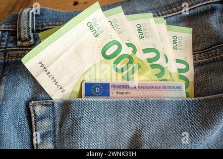 Hundert-Euro-Scheine und EU-Führerschein in Jeans-Tasche 03.03.24, Limburg: Symbolfoto, Illustrationsbild, Symbolbild, Illustrationsfoto Hundert-Euro-Scheine und EU-Führerschein in Jeans-Tasche das Bild präsentiert eine detailreiche Aufnahme, in der mehrere Hundert-Euro-Scheine zusammen mit einem EU-Führerschein in der Gesäßtasche einer blauen Jeans steckt. Die Jeans und der Führerschein sind nur im Anschnitt zu erkennen, wodurch das Augenmerk auf die Wertgegenstände in der Tasche gerichtet wird. Limburg Hessen Deutschland *** Hundert Euro-Scheine und EU-Führerschein in Jeanstasche 03 03 24, Li Stockfoto