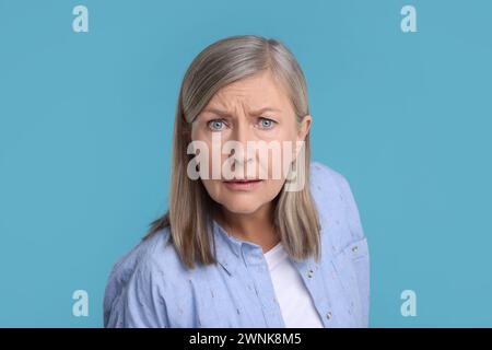 Porträt einer überraschten Seniorin auf hellblauem Hintergrund Stockfoto