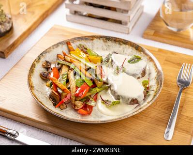 Gegrillte Schweinekoteletts mit geröstetem Gemüse, serviert mit Sauce, Restaurant-Menü Stockfoto