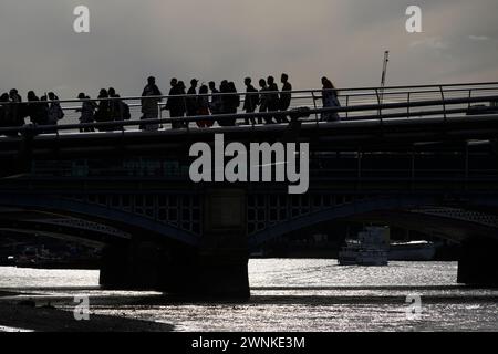 Die Silhouette von Fußgängern, die die Millennium Bridge überqueren, die die Themse überspannt. Millennium Footbridge, London, Großbritannien. Juli 2023 Stockfoto