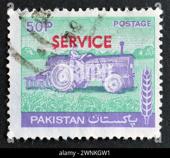 Gestempelte Briefmarke, gedruckt von Pakistan, auf der eine Traktorfahrerin zu sehen ist, überdruckt, um 1978. Stockfoto