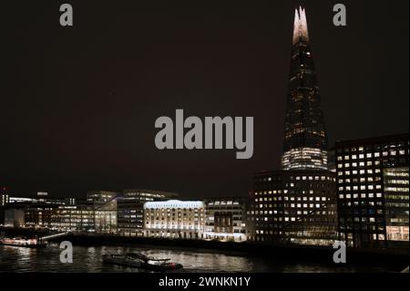 Kraftvolle abstrakte, architektonisch beleuchtete Nachtlandschaft der Shard und der Themse, aufgenommen von der London Bridge und zeigt Tooley Street, London Bridge Hospital, HMS Belfast, London Bridge City Pier und River Boats Stockfoto