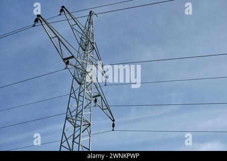 Isolierter Hochspannungs-Sendeturm, der an sonnigen Tagen Stromleitungen gegen blauen Himmel unterstützt. Negativer Raum. Einfach. Stockfoto
