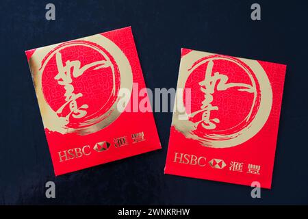 Roter Umschlag für das chinesische Neujahr (hongbao auf Mandarin) mit Geld. Chinesische Schriftzeichen lesen „Gute Wünsche“ oder „wie man will“. Gesponsert von HSBC Stockfoto