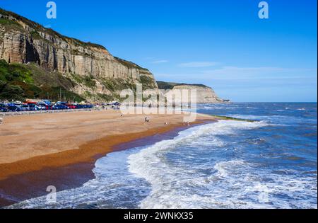 Panoramablick auf die Wellen am Shingle Rock-a-Nore Beach und die Klippen an der Küste von Hastings, East Sussex, England an einem sonnigen Tag Stockfoto