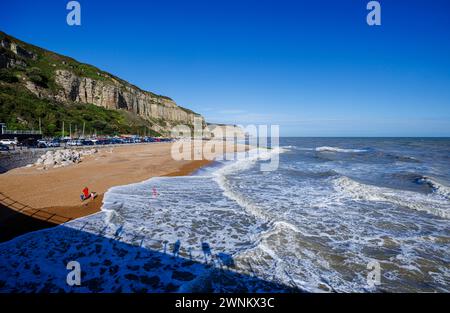 Panoramablick auf die Wellen am Shingle Rock-a-Nore Beach und die Klippen an der Küste von Hastings, East Sussex, England an einem sonnigen Tag Stockfoto