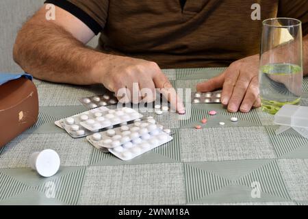 Pillen liegen zufällig auf dem Tisch. Der Mann versucht, einen vom Tisch zu nehmen. Stockfoto