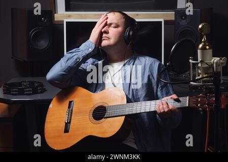 Trauriger Musiker, der seinen Kopf im Aufnahmestudio hält und seine Stimme verliert. Arbeitsplatz eines Tontechnikers in einem Tonstudio Stockfoto