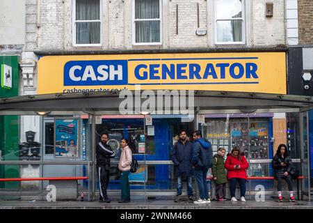 Slough, Berkshire, Großbritannien. März 2024. Die Leute warten auf einen Bus vor einem Cash Generator Laden in der Slough High Street, Berkshire. Kredit: Maureen McLean/Alamy Stockfoto