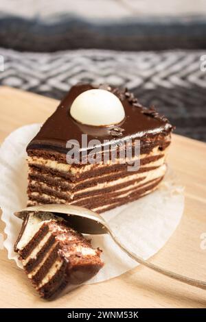 Schokoladenkuchen mit Löffel. Kekskuchen mit geschmolzener Ganache darauf. Scheibe cremige Torte. Dessert mit Vanille und Kakaoschicht. Süßes Food-Konzept. Stockfoto