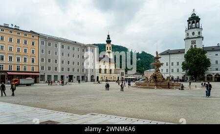 Offener Stadtplatz mit Brunnen und Menschen, eingerahmt von klassischen Gebäuden, Salzburg, Österreich Stockfoto