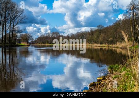 Ein ruhiger Fluss mit Bäumen entlang des Ufers reflektiert den blauen Himmel und weiße Wolken, Dortmund-Ems-Kanal, Emsland, Niedersachsen Stockfoto