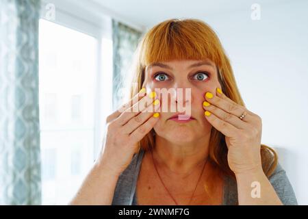 Porträt einer Frau mittleren Alters, rothaarig, Gesicht Nahaufnahme mit geschwollenen Augen, faltige Haut Stockfoto