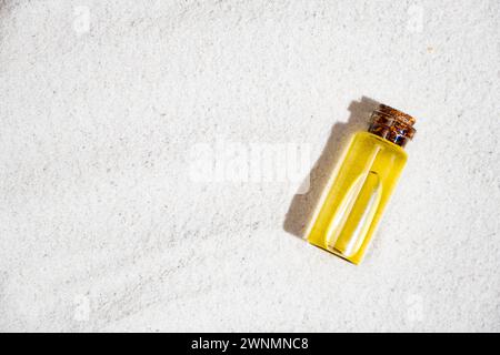 Ätherisches Öl in Glasflasche auf Sand, Draufsicht, Platz für Text. Stockfoto
