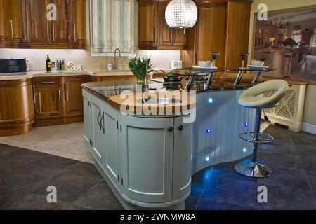 Moderne Küche mit Insel in modernem Stil mit Dunstabzugshaube Küche mit Lampe. Holztüren. Stockfoto