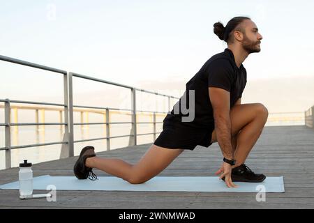 Mann beugt Beine im knienden Hüftbeuger-Dehnen beim Training im Freien Stockfoto