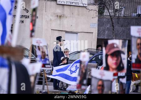 Jerusalem, Israel. März 2024. Ein israelischer Orthodoxer in Jerusalem beobachtet die Geiselfamilien beim Einzug in die Stadt am Shabbath. Familien der 134 israelischen Geiseln marschieren nach Jerusalem mit den Fotos ihrer Lieben, die 148 Tage lang in Gefangenschaft der Hamas im Gazastreifen gehalten wurden. Tausende Israelis marschieren in ihren viertägigen Protesttagen vom Parteigelände Nova zu einer Zeremonie in Jerusalem, während Gespräche über einen Waffenstillstand und Geiselabkommen stattfinden. (Credit Image: © Matan Golan/SOPA Images via ZUMA Press Wire) NUR REDAKTIONELLE VERWENDUNG! Nicht für kommerzielle ZWECKE! Stockfoto