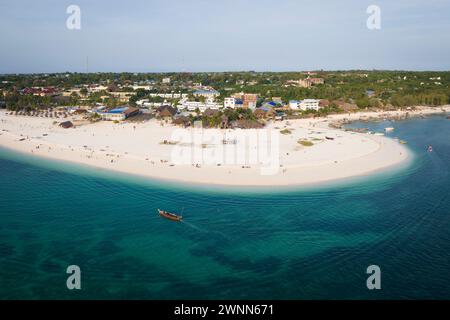 Blick von oben auf den Strand und das klare grüne Wasser an der tropischen Küste mit Sandstrand. Holzfischboot in der Nähe der Küste. Sommerreisen in Sansibar, Afrika, T Stockfoto