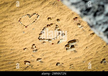 2 Herzen aus Felsen, flach auf dem braunen Sandstrand. Stockfoto