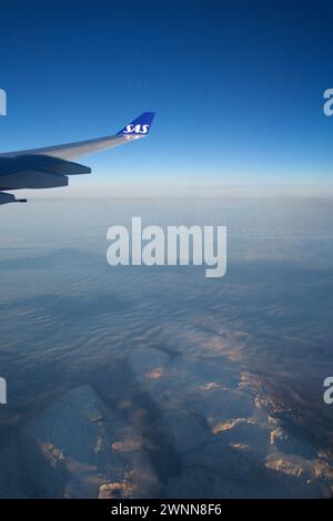 KOPENHAGEN, DÄNEMARK - 24. November 2018: Flugzeugfenster mit Flugzeugflügel, der bei Sonnenuntergang über die Eisberge Grönlands fliegt Stockfoto