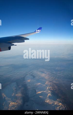 KOPENHAGEN, DÄNEMARK - 24. November 2018: Flugzeugfenster mit Flugzeugflügel, der bei Sonnenuntergang über die Eisberge Grönlands fliegt Stockfoto