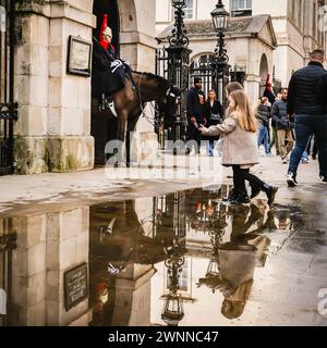 London, Großbritannien. März 2024. Touristen spiegeln sich in den vielen großen Pfützen des jüngsten schweren Regenfalls wider, während sie sich um die berittenen Wachen der King's Life Guard by Horse Guards Parade auf Whitehall in Westminster versammeln. Am Nachmittag sah man in London wunderschöne Sonne, nach Tagen mit starken Schauern. Quelle: Imageplotter/Alamy Live News Stockfoto