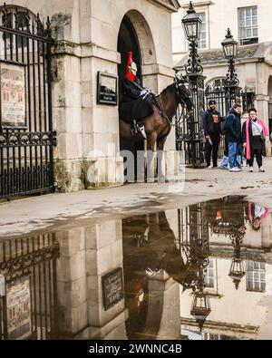 London, Großbritannien. März 2024. Touristen spiegeln sich in den vielen großen Pfützen des jüngsten schweren Regenfalls wider, während sie sich um die berittenen Wachen der King's Life Guard by Horse Guards Parade auf Whitehall in Westminster versammeln. Am Nachmittag sah man in London wunderschöne Sonne, nach Tagen mit starken Schauern. Quelle: Imageplotter/Alamy Live News Stockfoto