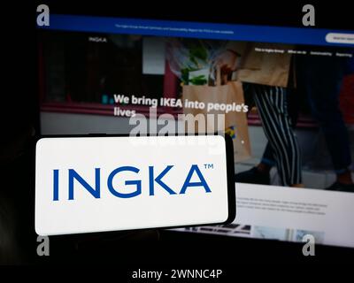 Person mit Smartphone und Logo der niederländischen Firma INGKA Holding B.V. vor der Website. Schwerpunkt auf dem Display des Telefons. Stockfoto