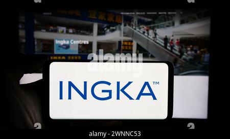 Person, die ein Mobiltelefon mit dem Logo der niederländischen Firma INGKA Holding B.V. vor der Webseite hält. Schwerpunkt auf dem Display des Telefons. Stockfoto