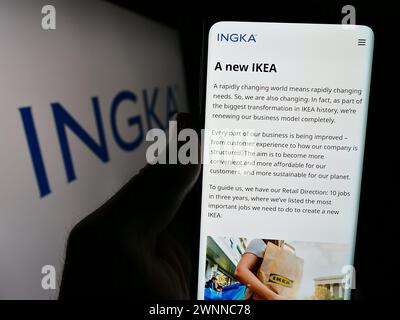 Person mit Smartphone und Website der niederländischen Firma INGKA Holding B.V. vor dem Firmenlogo. Konzentrieren Sie sich auf die Mitte des Telefondisplays. Stockfoto