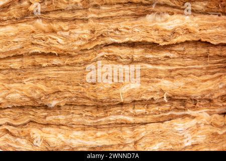 Nahaufnahme der Mineralwolle-Füllung, die als Isolierung in der Wand verwendet wird. Gelbe Mineralwolle mit sichtbarer Textur. Stockfoto