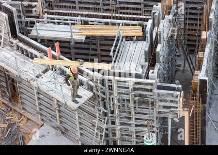 Der Arbeiter trägt eine Holzdiele auf eine Betonschalung Stockfoto