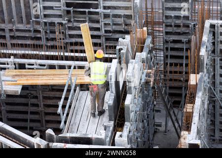 Der Arbeiter trägt eine Holzdiele auf eine Betonschalung Stockfoto