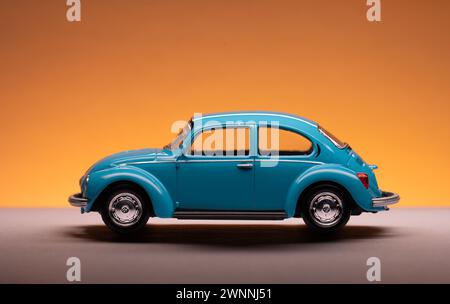 Göteborg, Schweden - 27. Februar 2024: Blauer Volkswagen Käfer Spielzeugwagen auf orangem Hintergrund Stockfoto
