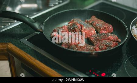 Große, fette, saftige Steaks in einer Pfanne, gewürzt, fertig zum Grillen. Ein Fleischessen in einer Pfanne zubereiten Stockfoto
