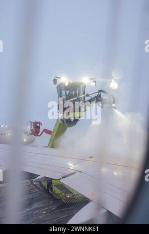 Enteisung oder Enteisung eines Luftfahrzeugs vor dem Start. Sicherheitsmaßnahmen bei kalten Umgebungstemperaturen am Flughafen, um ein Einfrieren der Kontrollflächen zu verhindern. Stockfoto