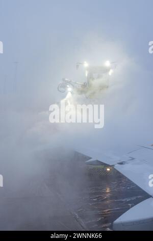 Enteisung oder Enteisung eines Luftfahrzeugs vor dem Start. Sicherheitsmaßnahmen bei kalten Umgebungstemperaturen am Flughafen, um ein Einfrieren der Kontrollflächen zu verhindern. Stockfoto