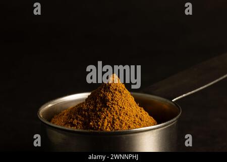 Ein Haufen Zimt in einem Messlöffel aus Metall. Stockfoto