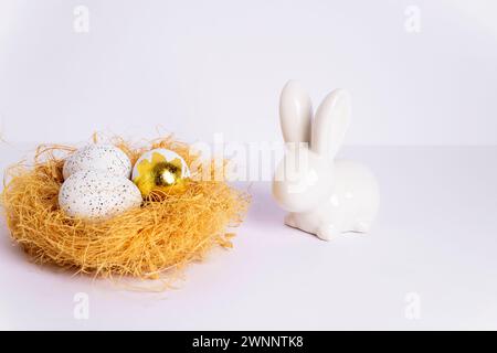 Nest mit Ostereiern und Häschen auf weißem Tisch. Nahaufnahme. Stockfoto