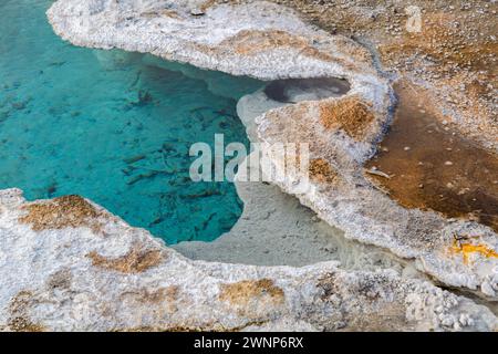 Nahaufnahme von Minerallagerstätten am Rand eines klaren blauen Geysirs im Upper Geyser Basin im Yellowstone-Nationalpark Stockfoto