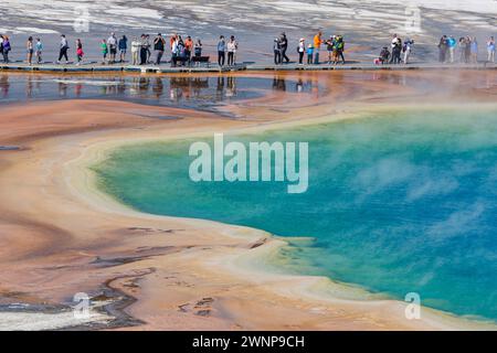 Parkbesucher auf der Aussichtsplattform können die Grand Prismatic Spring im Midway Geyser Basin des Yellowstone National Park, Wyomin, aus nächster Nähe betrachten Stockfoto