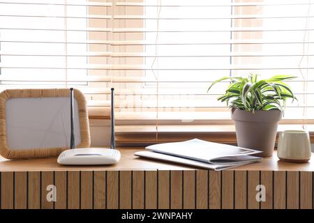 Moderner wlan-Router mit Rahmen und Magazinen im Zimmer Stockfoto