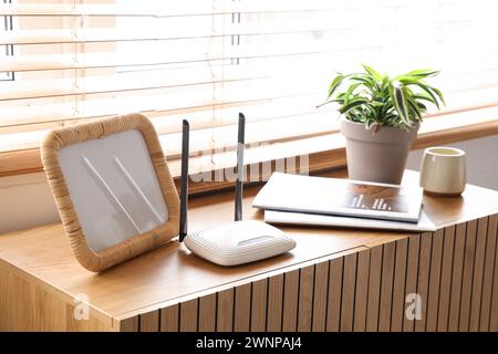 Moderner wlan-Router mit Rahmen und Magazinen im Zimmer Stockfoto