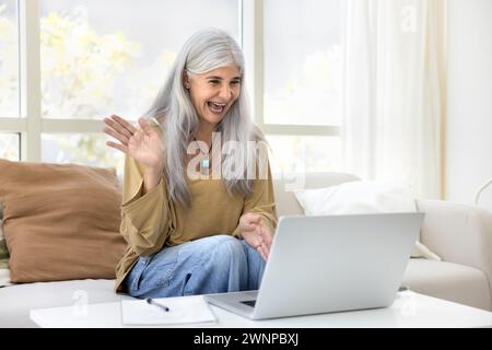 Fröhliche grauhaarige ältere Lateinfrau, die im Videoanruf spricht Stockfoto