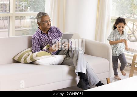 Konzentrierter indischer Großvater mit Online-Geschäftsanwendung und Finanzdienstleistungen Stockfoto